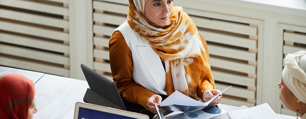3 woman are looking over a digital advertising presentation. They are also looking thorough documents.